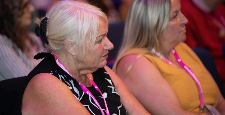 Two women sitting in a row watching something off camera