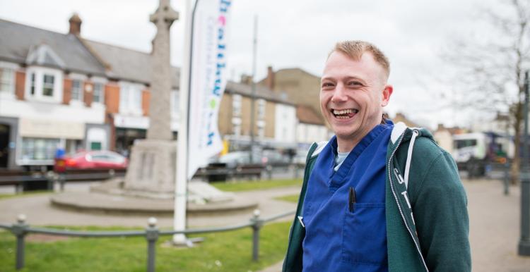 Man wearing scrubs stood in front of a Healthwatch banner