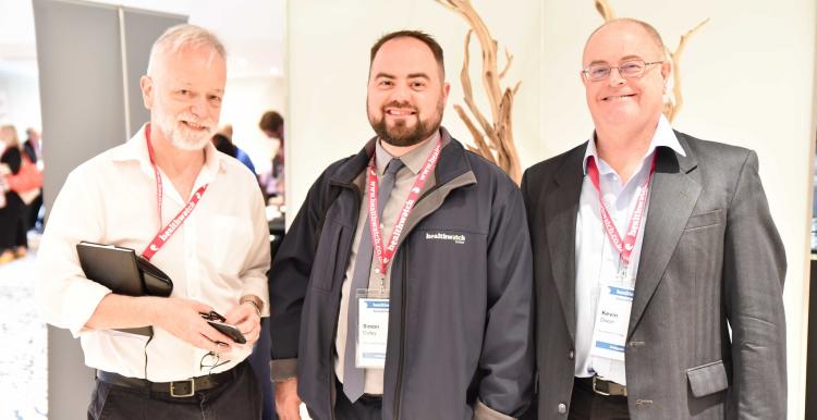 Three men, two of which have beards, standing at an indoor event