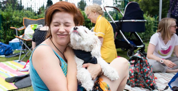 Woman smiling and holding her dog in the park 