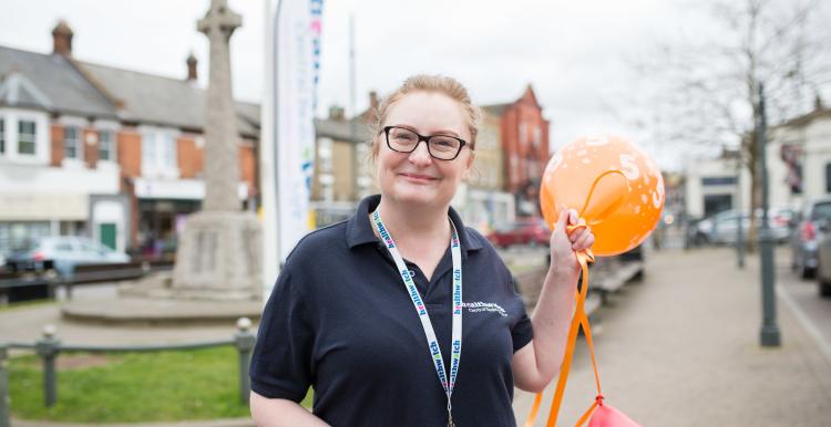 Healthwatch volunteer stood outside holding balloons