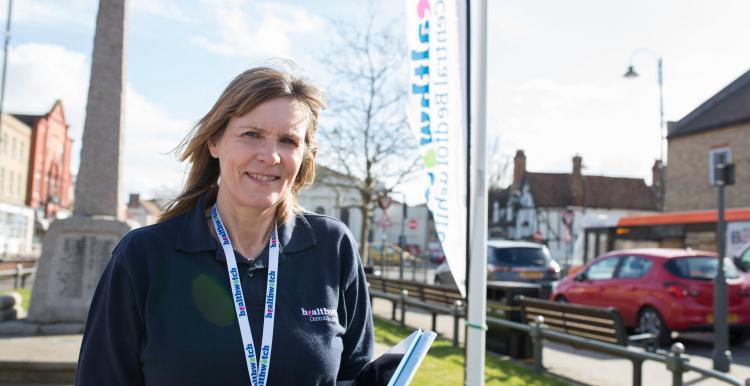 Healthwatch volunteer standing in front of a Healthwatch banner